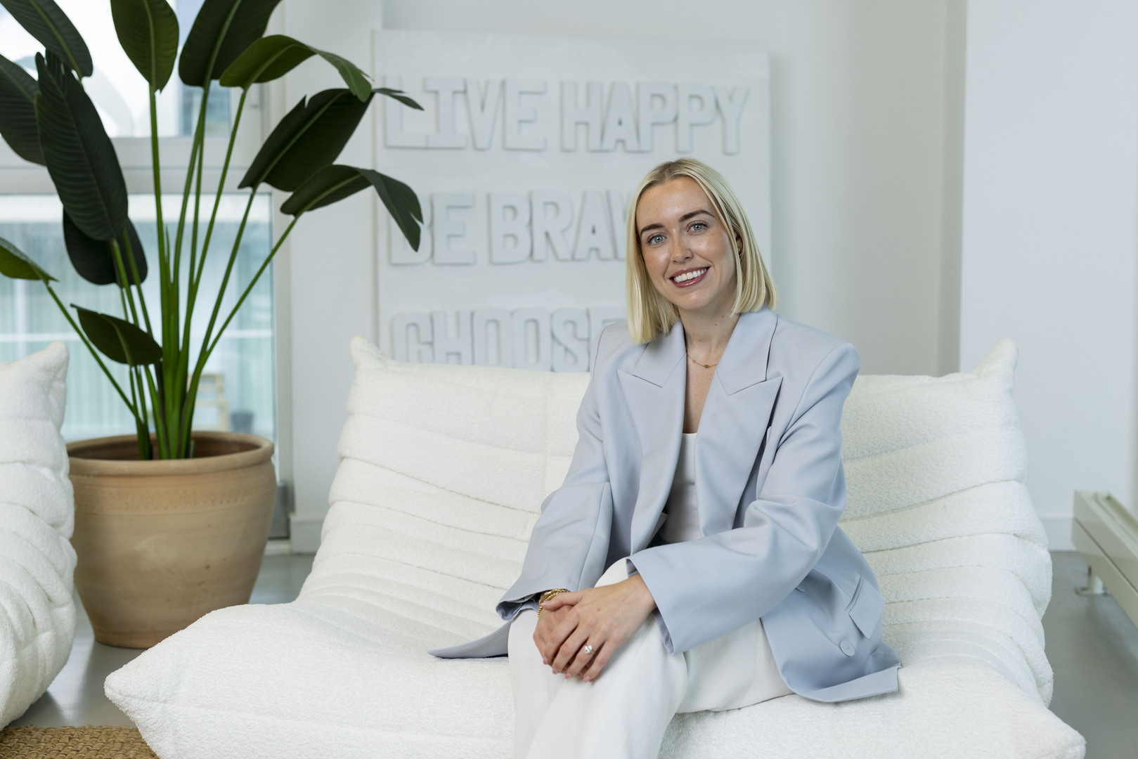 Olivia Jenkins, founder of D.Louise, sitting on a white couch in her London office.
