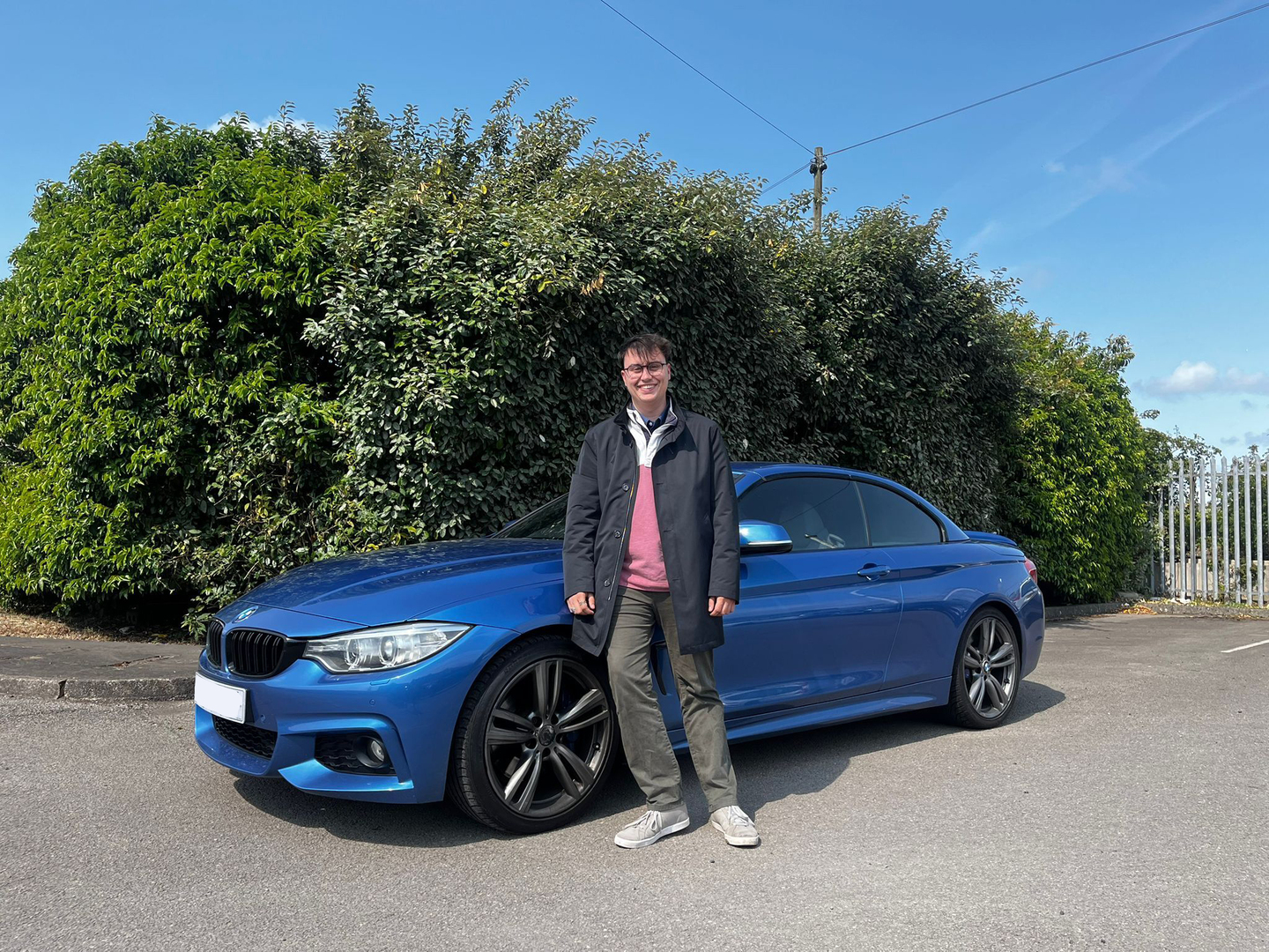 Isaac Chadwick standing next to his blue BMW F33 420D.